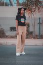 Woman in Black Crew Neck T-shirt and White Pants Standing on Gray Concrete Floor during