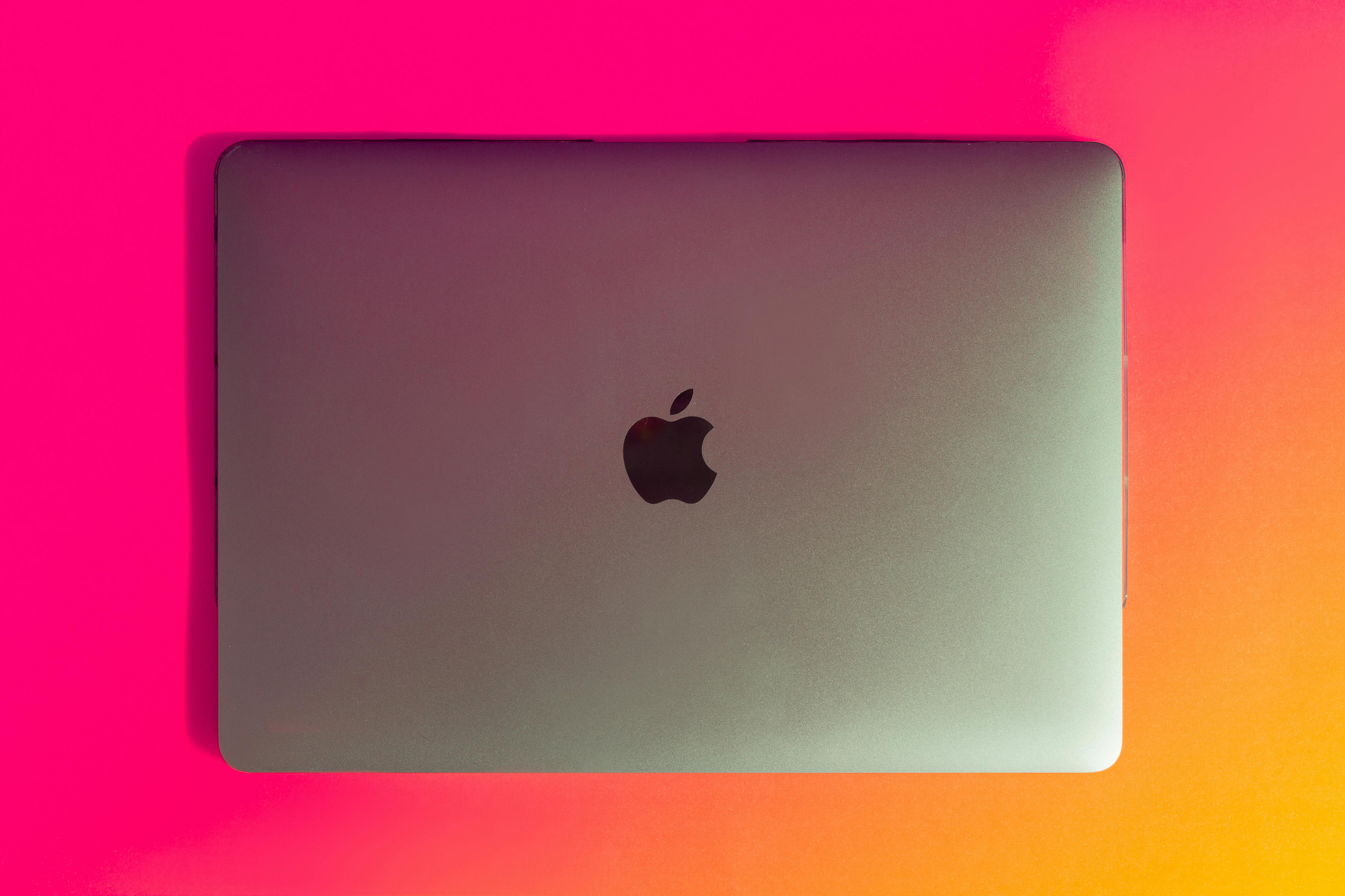 Top view of a modern laptop on a vibrant pink and orange gradient background. Perfect for tech and design concepts.