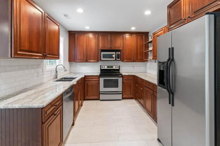 A Kitchen With Wooden Cabinets And New Appliances 