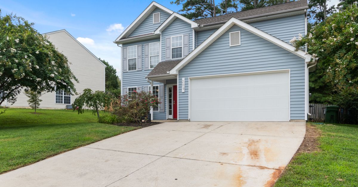 Charming two-story suburban house with spacious driveway and greenery.