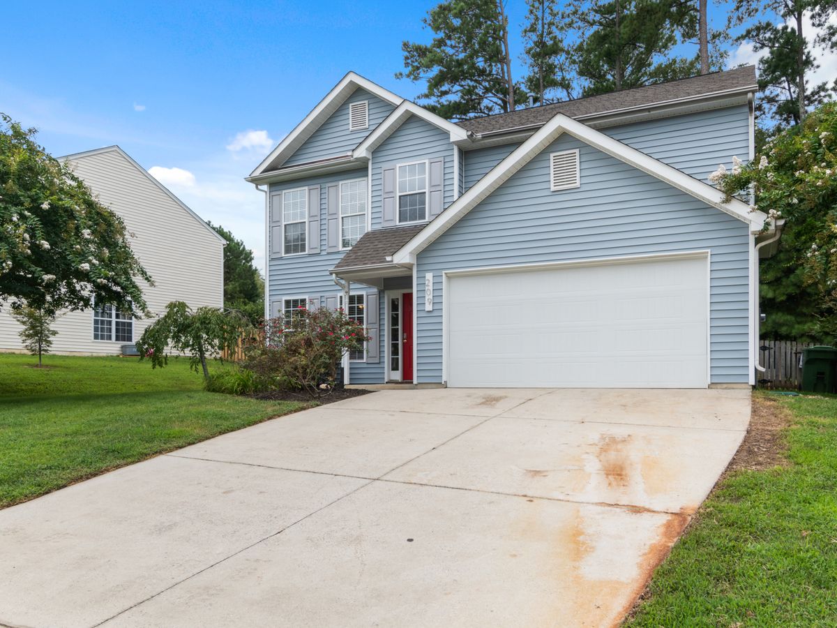 Two-story house with a driveway and greenery.