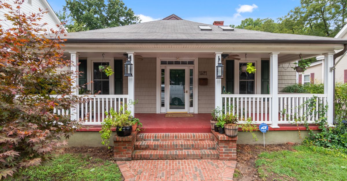 Inviting suburban house with a classic porch and lush garden, perfect for real estate listings.