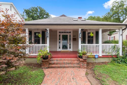 Free Inviting suburban house with a classic porch and lush garden, perfect for real estate listings. Stock Photo