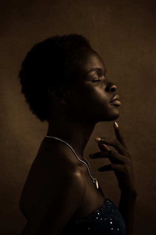 Young black woman with closed eyes touching chin