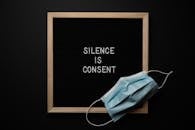 Composition of protective mask placed on wooden frame of blackboard on black background with lettering inspiring to speak up about problems