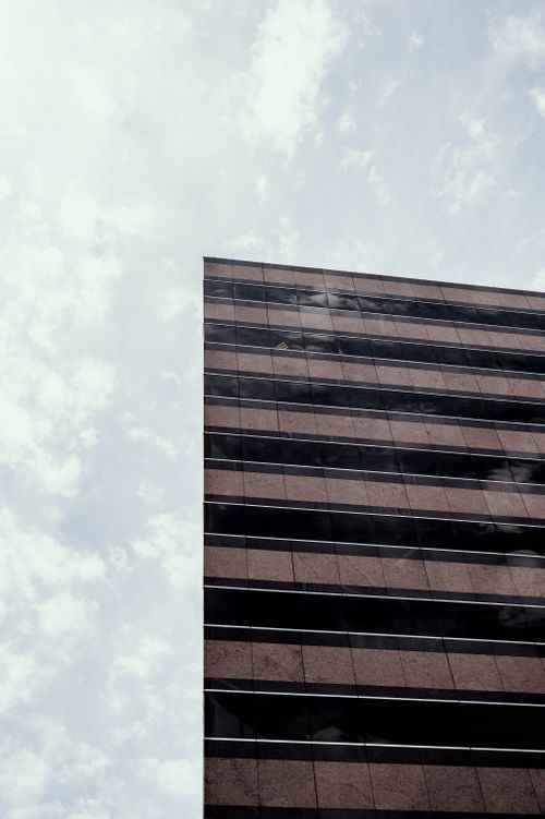Free From below of facade of office building with high wall without windows located against cloudy sky in city street outside Stock Photo