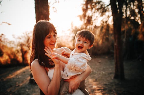 Happy woman holding baby in summer