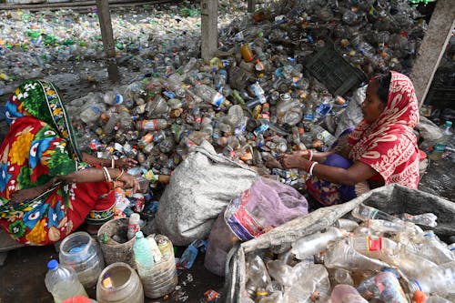 Free Woman Sitting on Recycled Trash of Plastic Bottles  Stock Photo