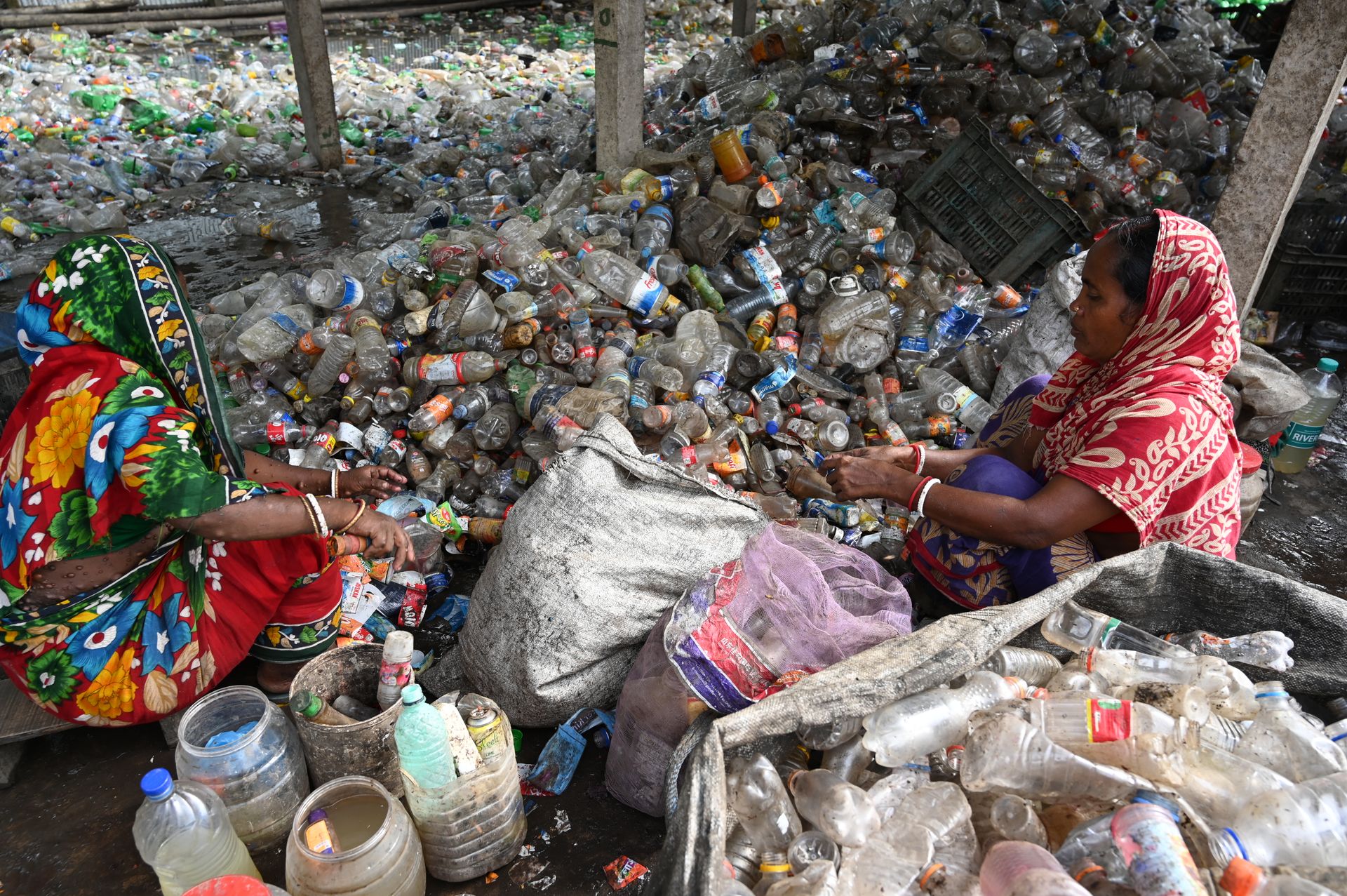 Two women sorting plastic bottles for recycling in Chattogram, Bangladesh.