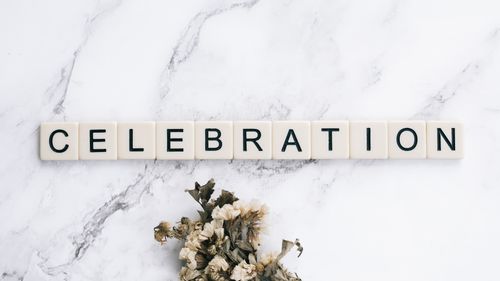 Free Scrabble tiles on marble spelling 'Celebration' with dried flowers. Stock Photo