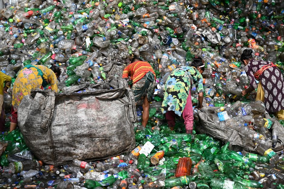 Workers sorting plastic waste at a landfill in Chattogram, Bangladesh. Environmental and recycling theme.