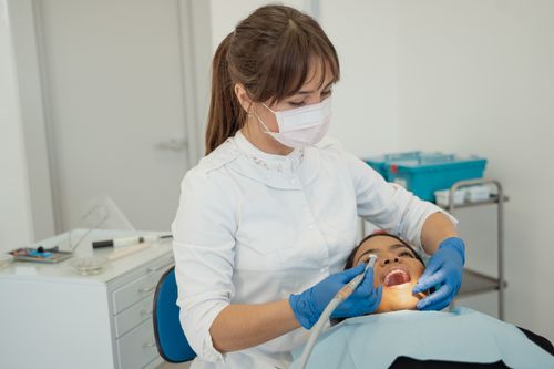 Free Dentist performing a routine dental check-up on a patient in a modern clinic setting. Stock Photo