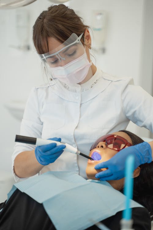 Dentist using a Dental Curing Light on a Patient 