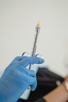 Close-up of a gloved hand holding a syringe for medical injection, highlighting healthcare practices.