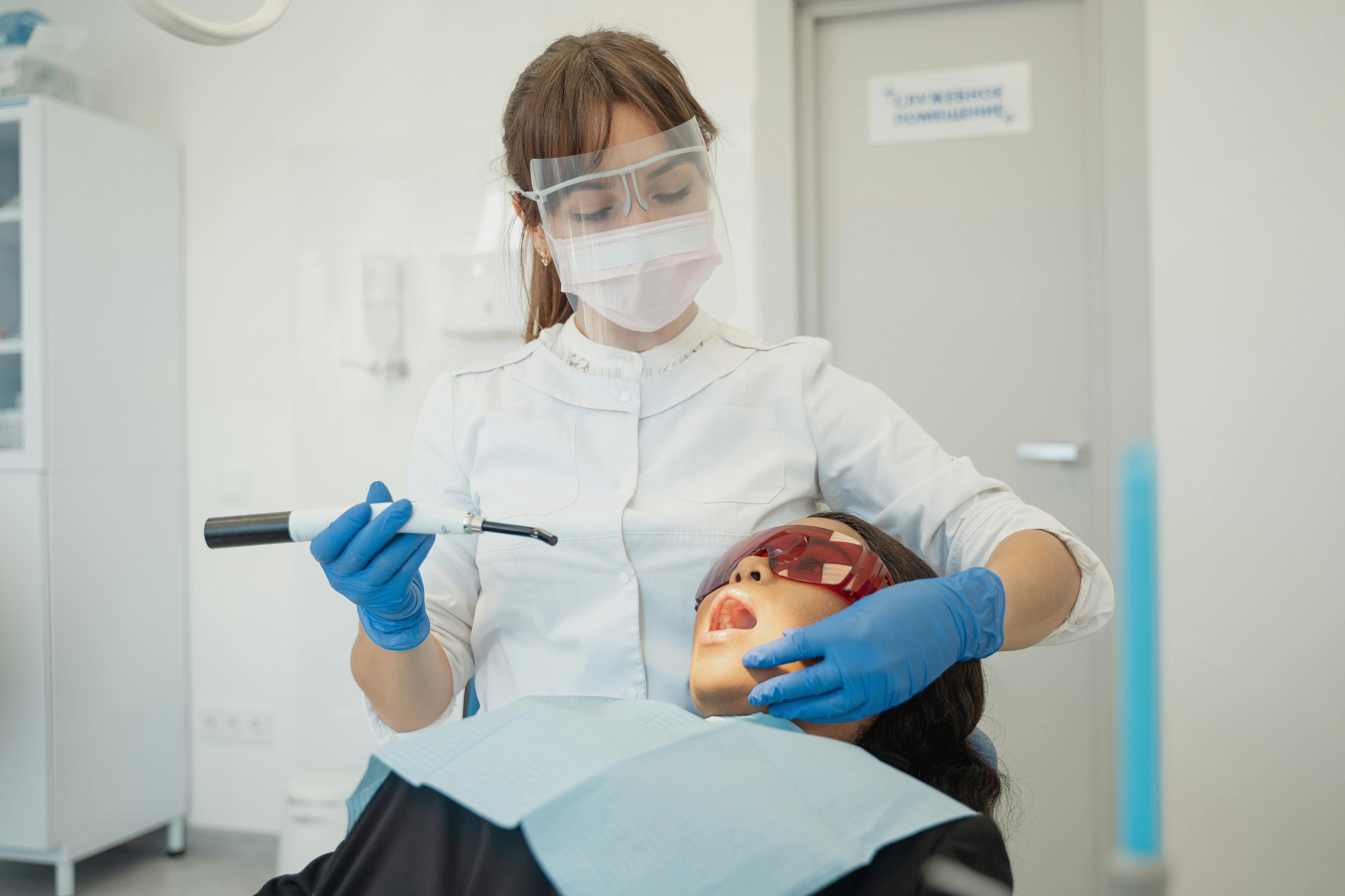 Female Dentist Using A Dental Curing Light On A Patient · Free Stock Photo