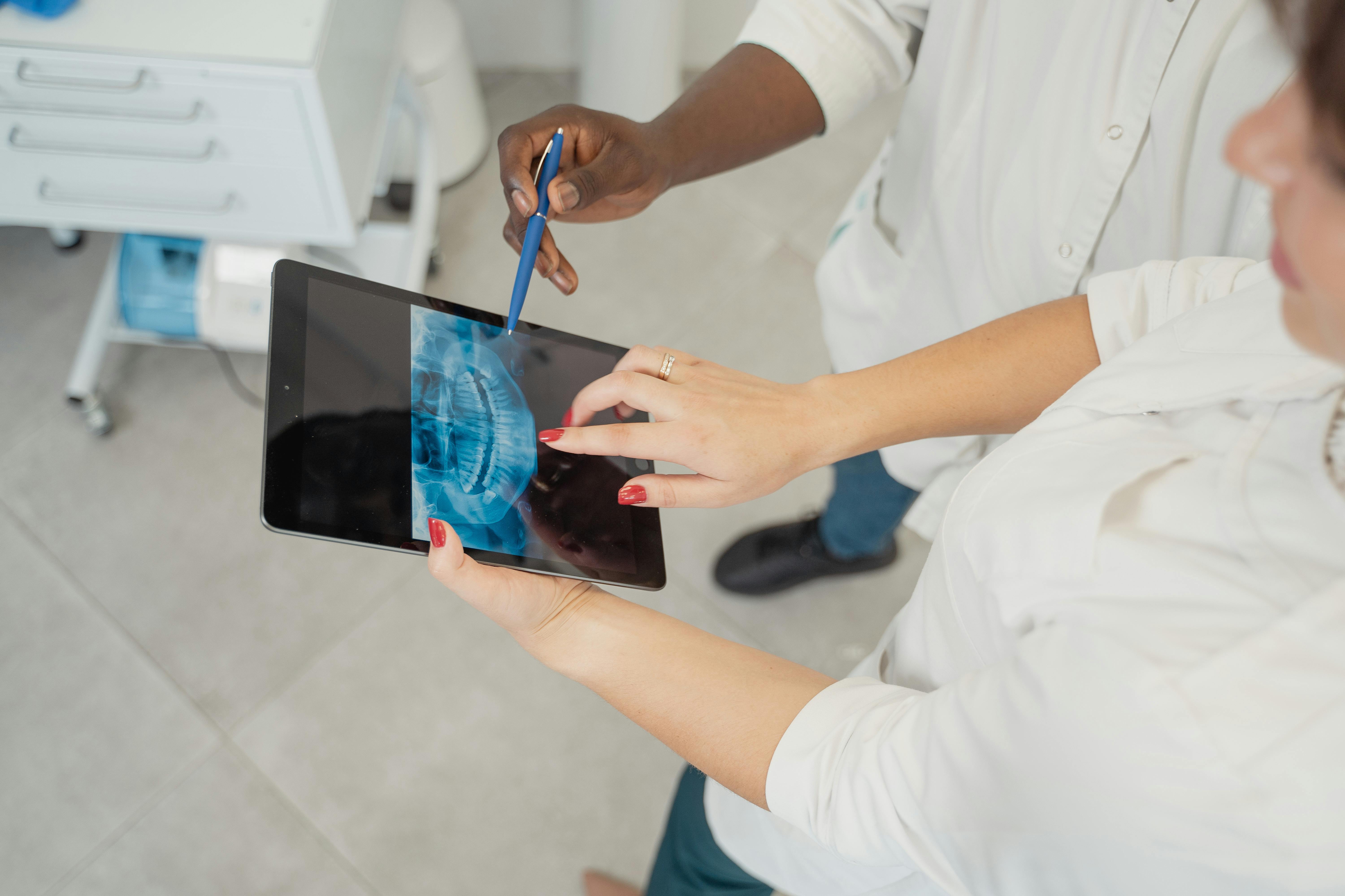 People Pointing at a Dental X-Ray Image on a Tablet