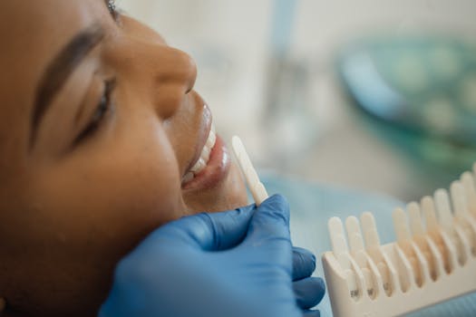 Smiling woman receiving a dental checkup with shade guide in the clinic.