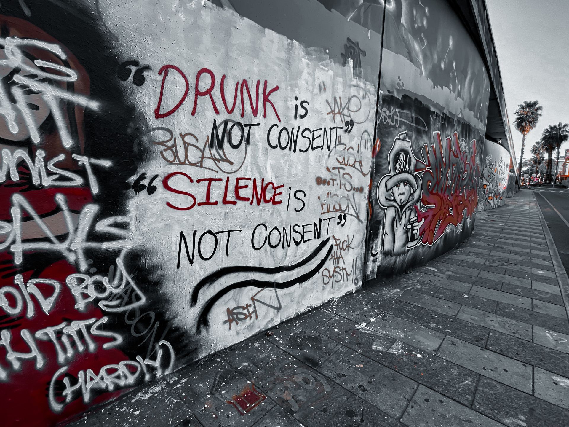 Graffiti art emphasizing consent with bold text on urban street wall.