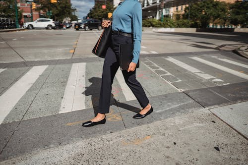 Crop woman walking on crosswalk