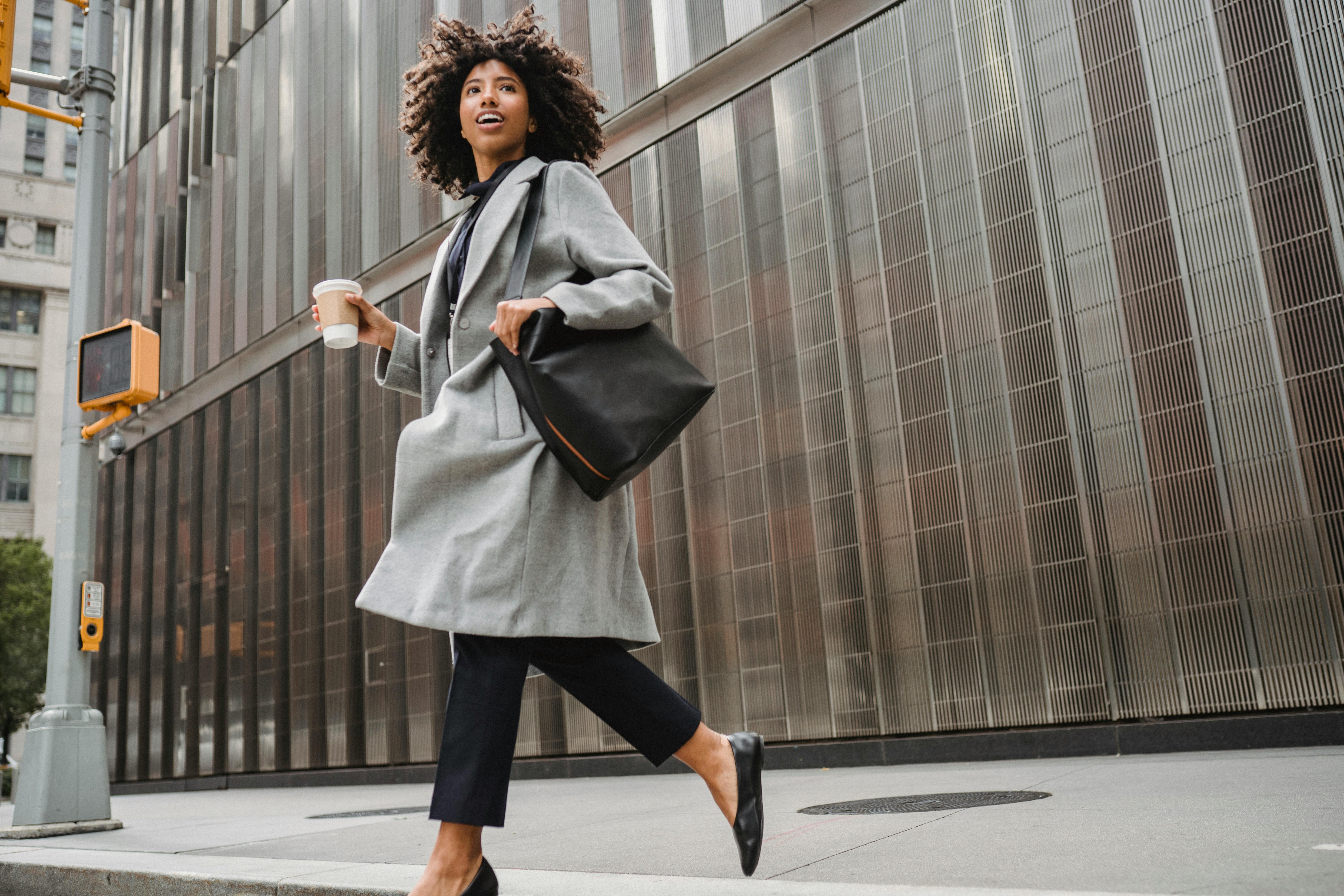 Free Photo  Stylish african american business woman with handbag on streets  of city and looking at watches