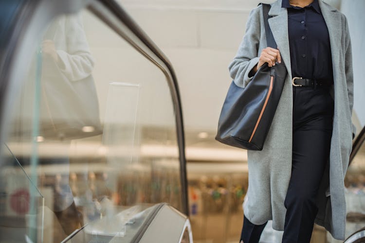 Crop Woman Standing On Escalator In Mall