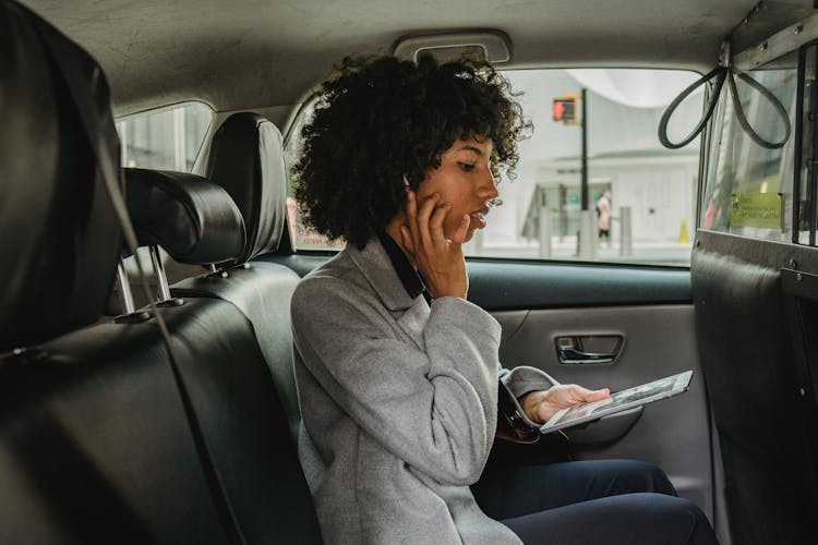 Businesswoman With Wireless Earphones And Tablet On Backseat