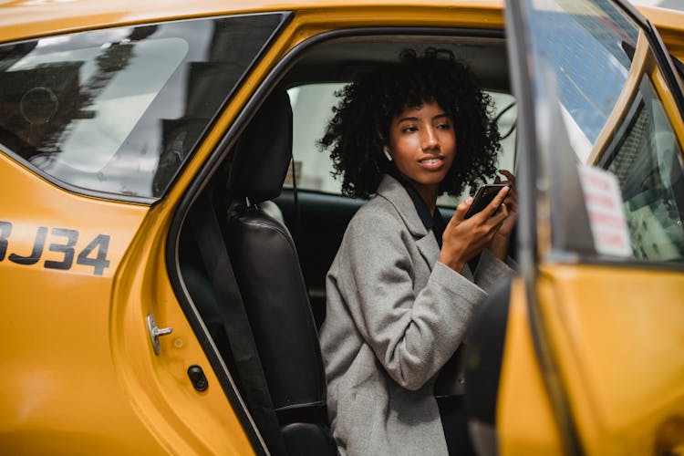 Black Woman Getting Out Of Taxi On Street