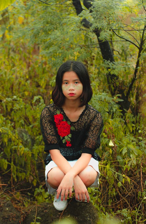 Teenage Girl Crouching with Lush Foliage Around 