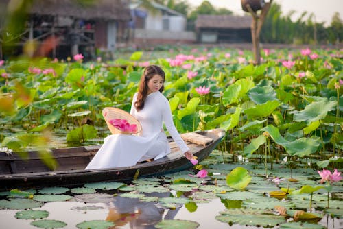 A Woman Looking at Lotus Flowers in a Pond while Sitting on a Boat
