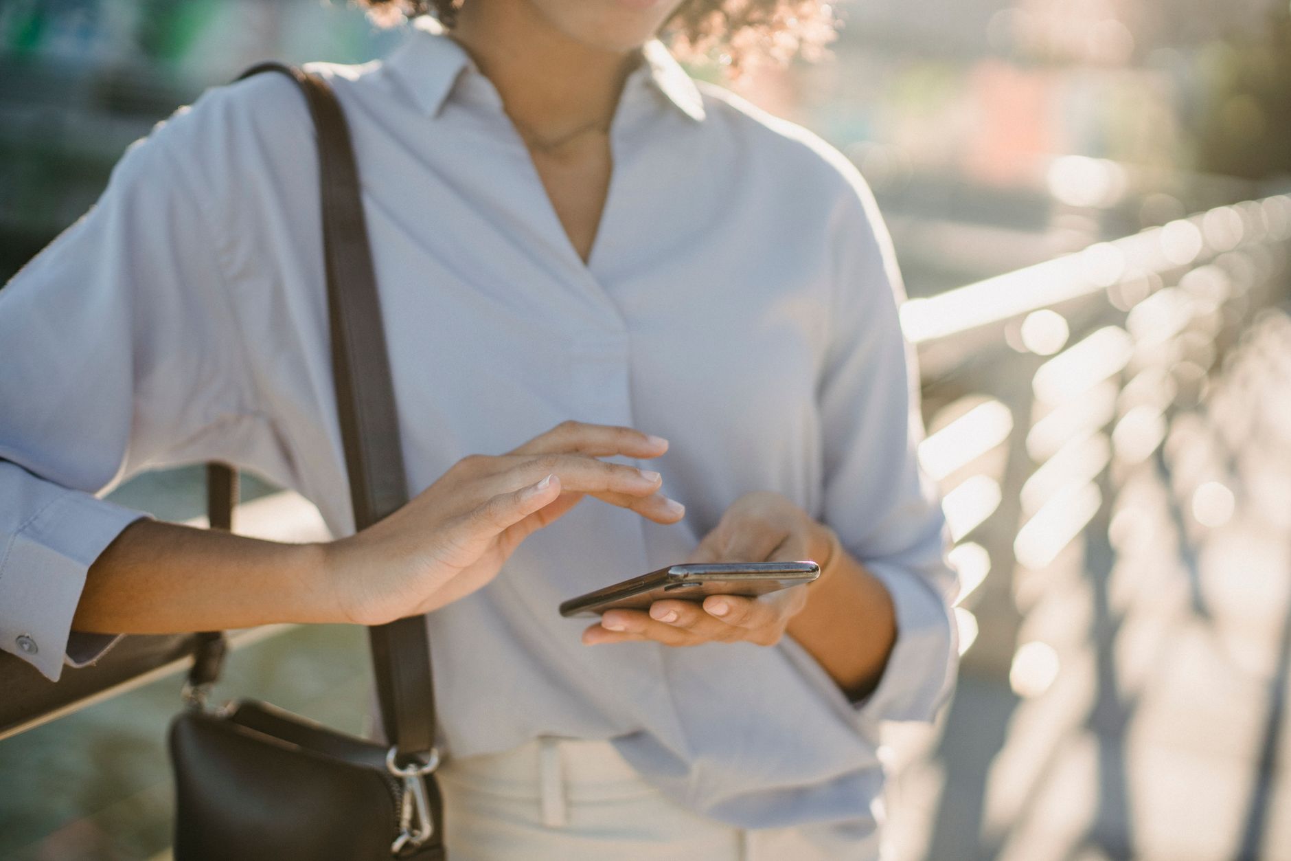 A woman interacts with her smartphone on a sunny day, creating a modern lifestyle scene.
