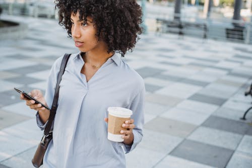 Woman Holding Coffee in Disposable Cup and Using Smart Phone 