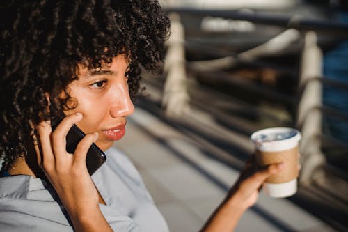 Photo of a Woman with Curly Hair Talking on Her Black Cell Phone