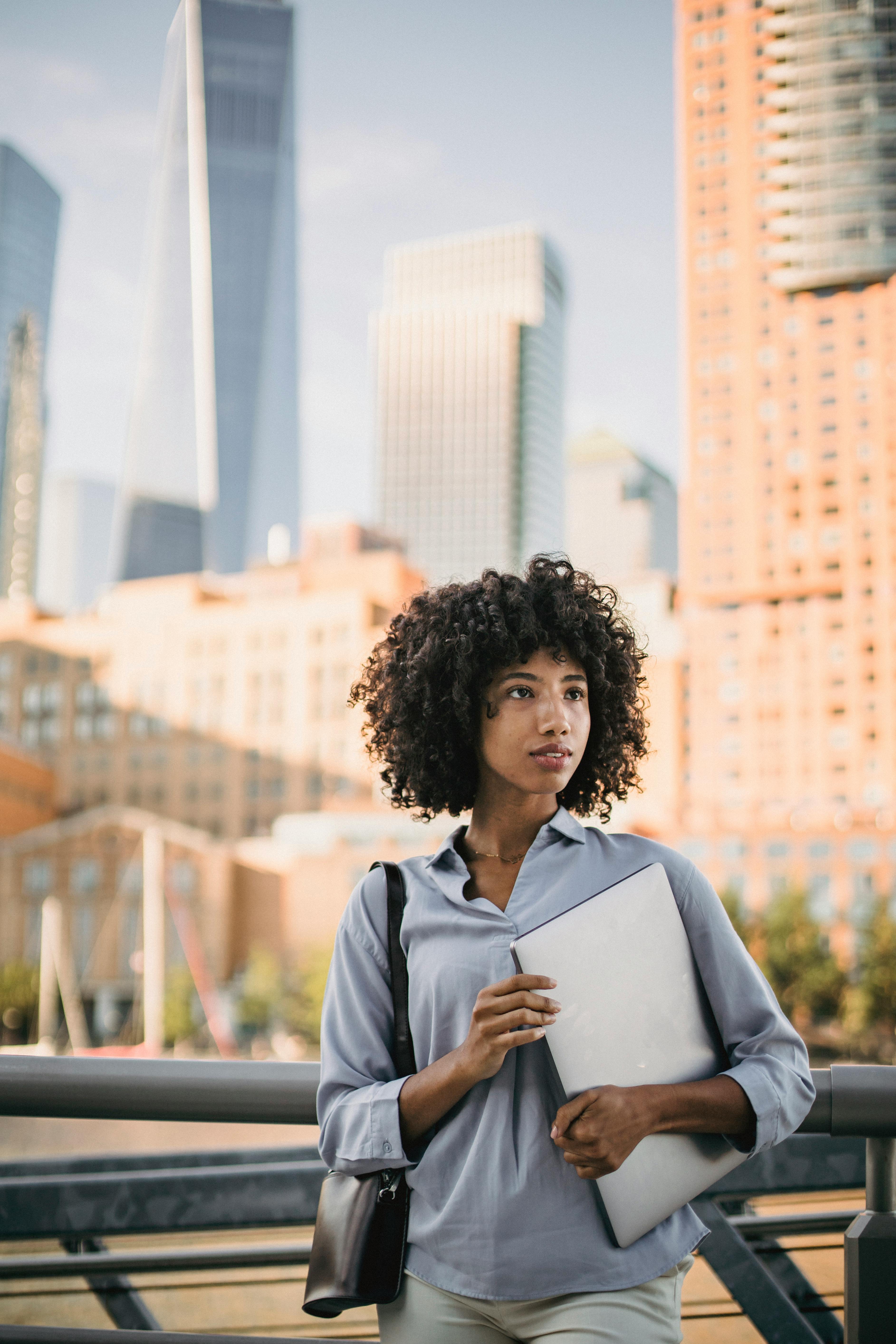在城市景观中，自信的女人使用笔记本电脑，体现了现代都市的职业生活