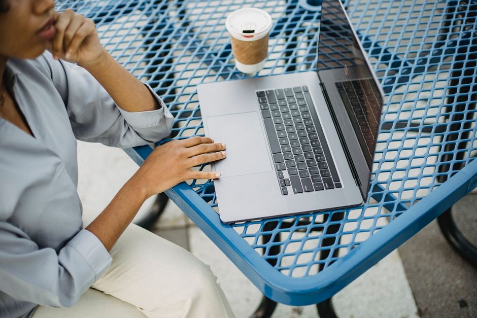 A woman working remotely with a laptop at an outdoor cafe table, focusing on productivity.