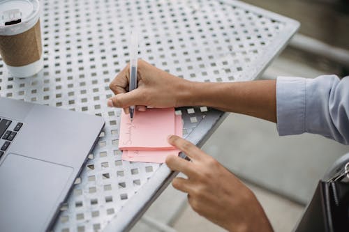 Free Photo of a Person's Hands Writing on a Pink Sticky Note Stock Photo