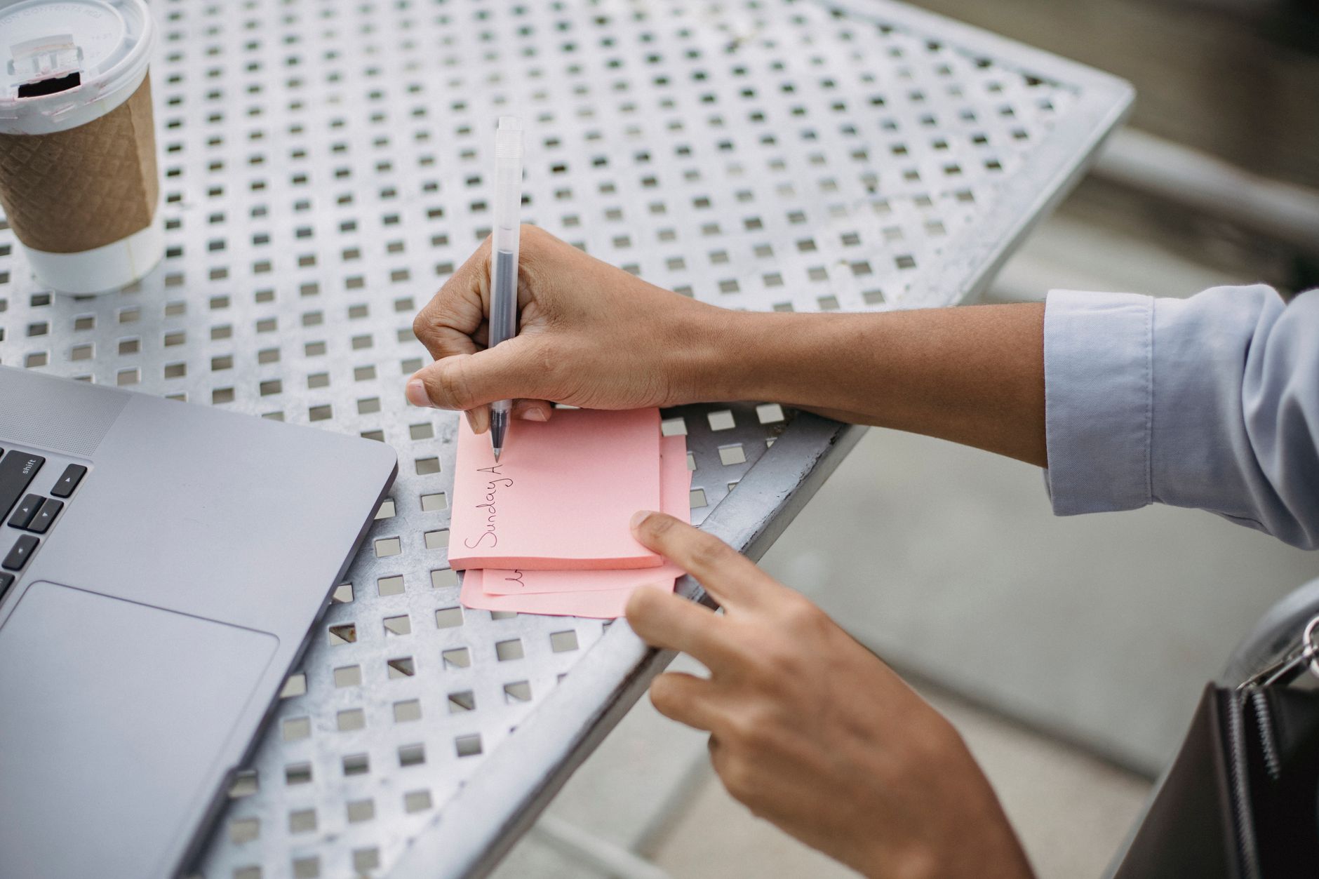 person typing on laptop with sticky notes and coffee