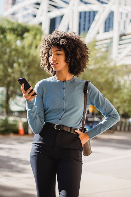 Photo of a Woman Texting while Her Hand is on Her Waist