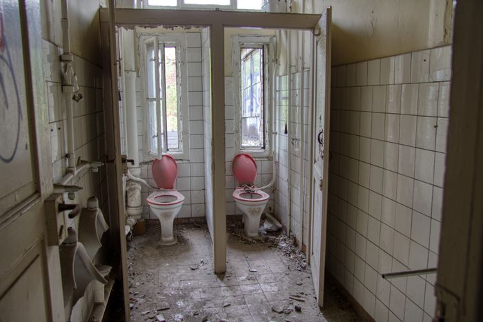 Old bathroom before renovation — broken fixtures and peeling tiles