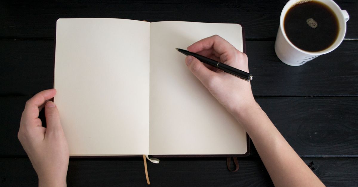 An open notebook with a pen rests next to a coffee cup — the kind of quiet workspace where retainer terms get written.