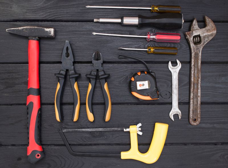 Close-up flat lay of assorted hand tools arranged on a dark wooden surface