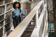 Woman in Blue Denim Jacket and Black Pants Standing on White Staircase