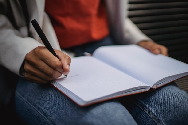 Person writing in a notebook for self-reflection