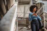 Woman in Blue Dress Shirt and Blue Denim Jeans Standing on Stairs