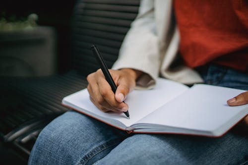 Photo of a Person's Hand Writing with a Black Pen