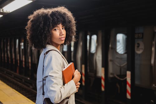 Free Photograph of a Woman with Curly Hair Holding a Brown Notebook Stock Photo