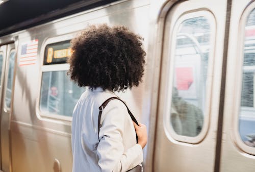 Back View of a Woman with Curly Hair Waiting at a Train Station