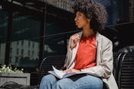 Woman in Gray Blazer and Orange Shirt Sitting on Gray Concrete Bench