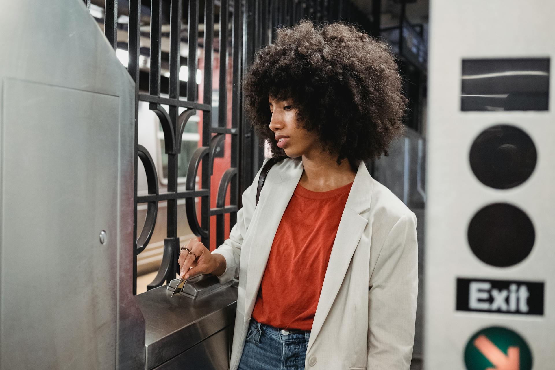 Young woman navigating a subway turnstile with a card in an urban station.