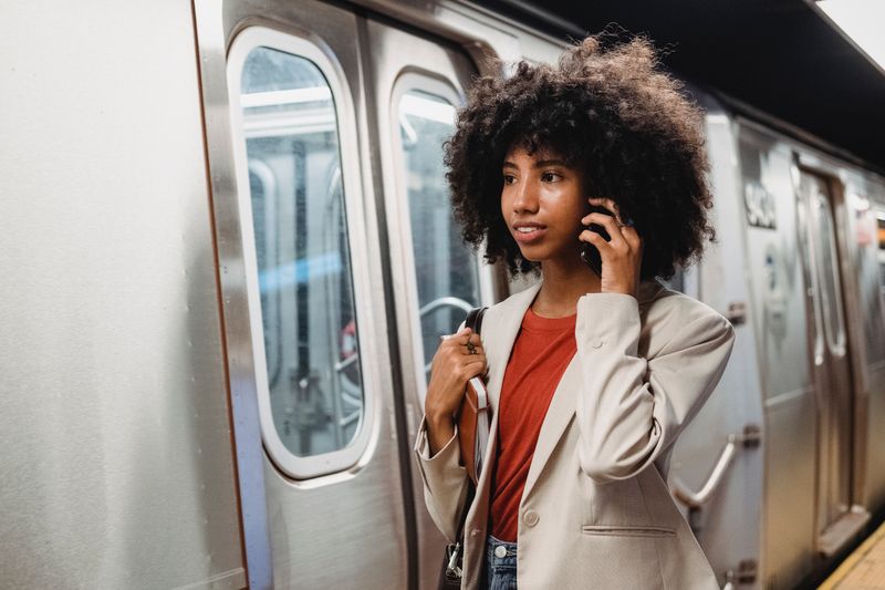 Confident woman in blazer using smartphone at subway station