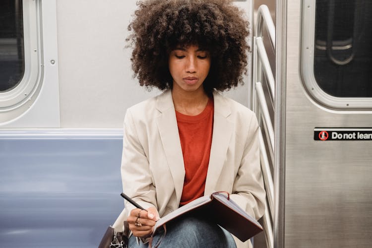 A Woman Writing In Her Journal While In A Train Ride